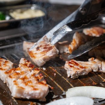 Korean BBQ meat being turned on a tabletop grill at Piggy Ssonday