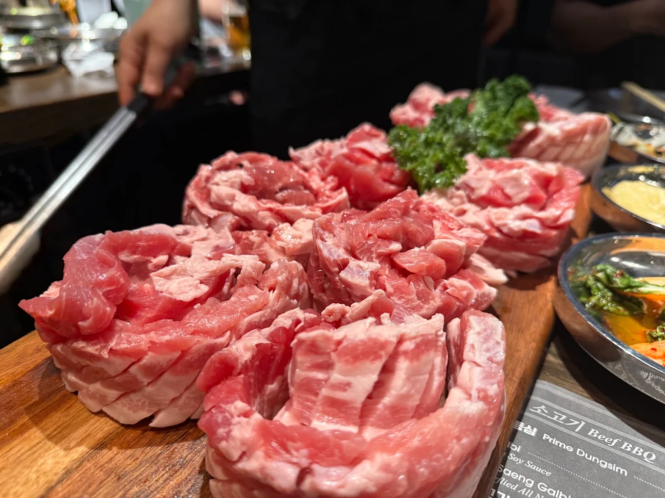Assorted fresh beef and pork BBQ cuts arranged on a wooden board at Piggy Ssonday
