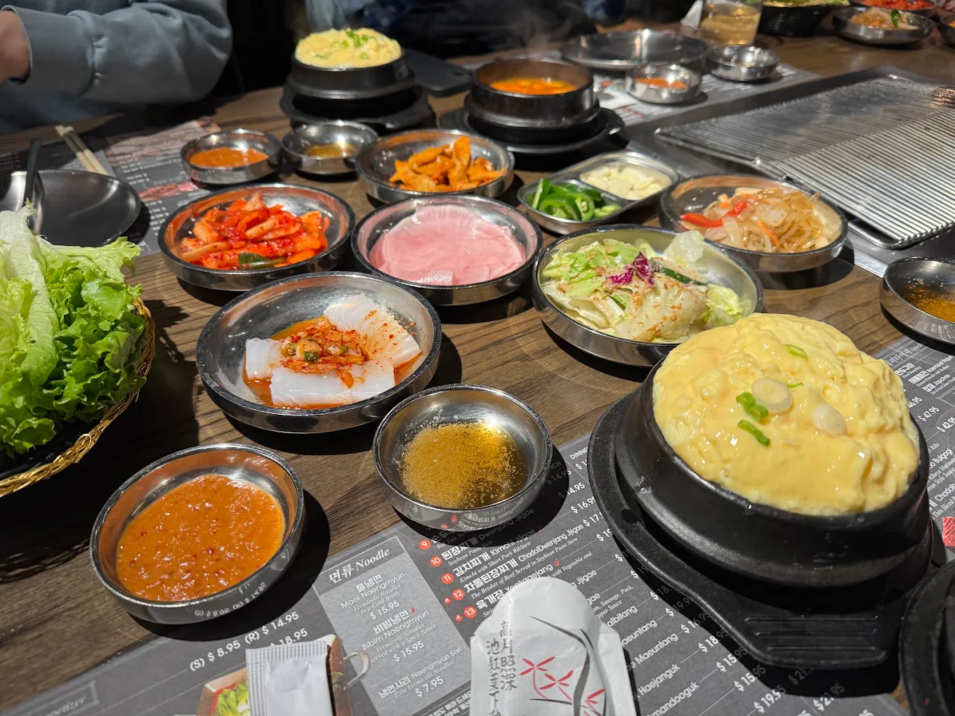 Table spread of banchan, steamed egg, stews and grill at Piggy Ssonday